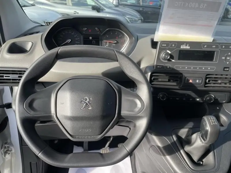 Vue intérieure centrée sur le volant Peugeot noir et la console centrale avec levier de vitesse manuelle du Rifter blanc 2020.