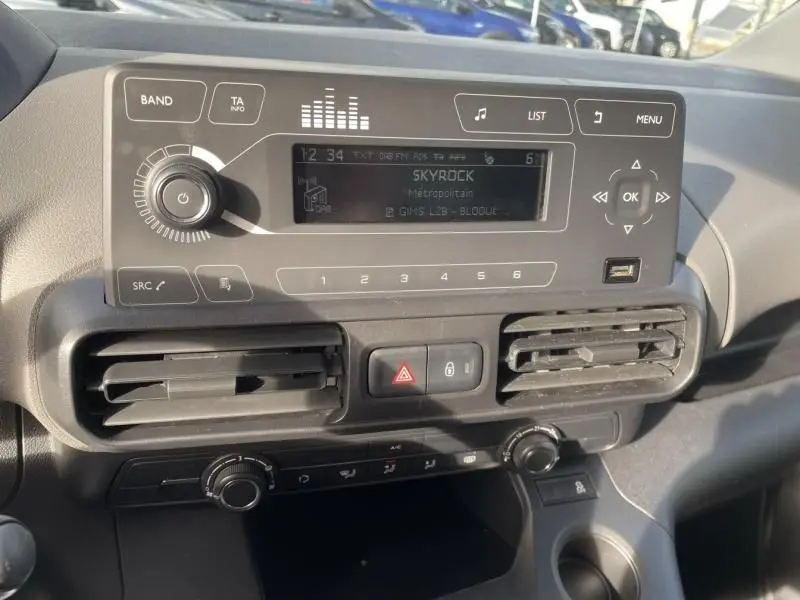 Tableau de bord du Peugeot Rifter blanc 2020, vue rapprochée sur la console centrale avec radio et commandes climatiques.