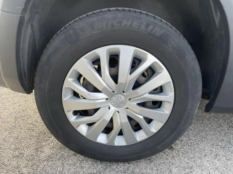Gros plan sur la roue avant droite d’un Peugeot Rifter blanc 2020, avec jante argentée et pneu Michelin visible.
