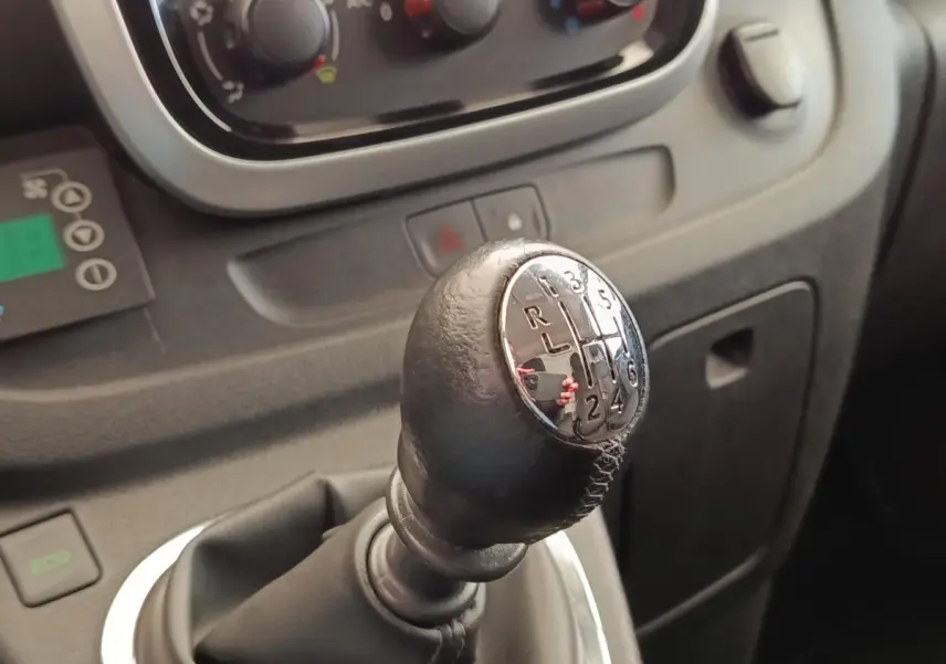 Le levier de vitesses manuel noir du Renault Trafic Fourgon 2017 vu en gros plan dans l'habitacle.