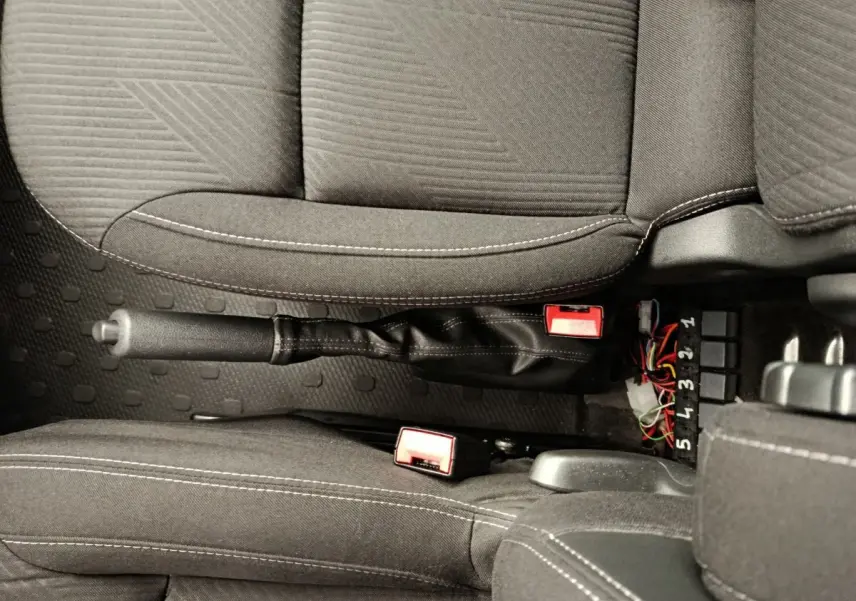 Vue rapprochée de l'intérieur du Renault Trafic Fourgon 2017, montrant la console centrale avec frein à main et ceintures noires.