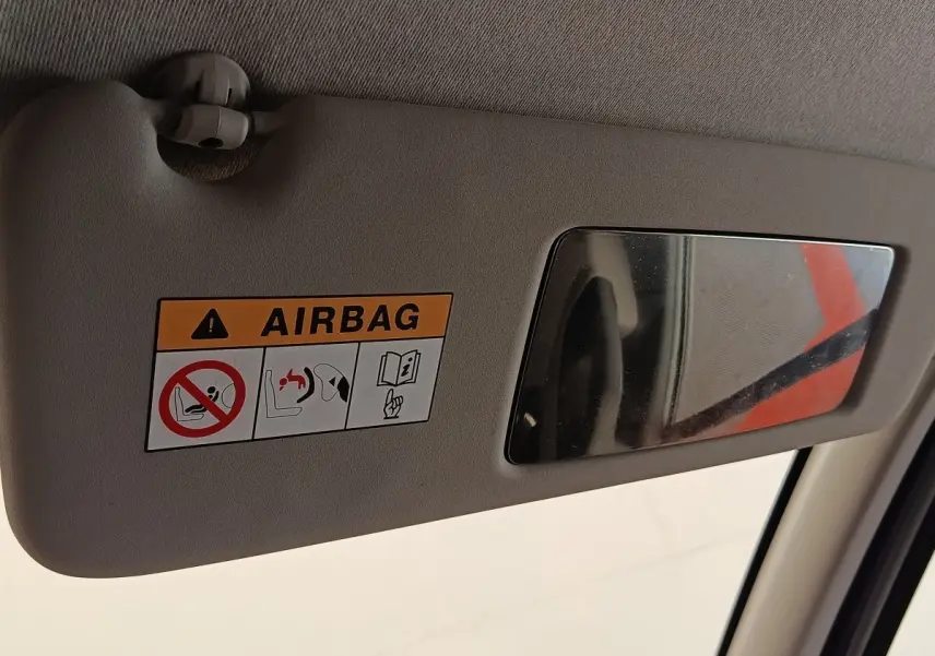 Détail du pare-soleil côté conducteur beige avec miroir et étiquette d'avertissement airbag dans un Renault Trafic blanc.