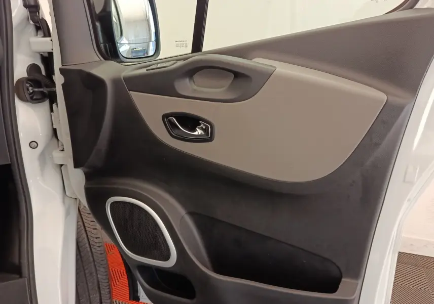 Gros plan sur la porte avant gauche blanche du Renault Trafic Fourgon, avec poignée et haut-parleur intégrés.