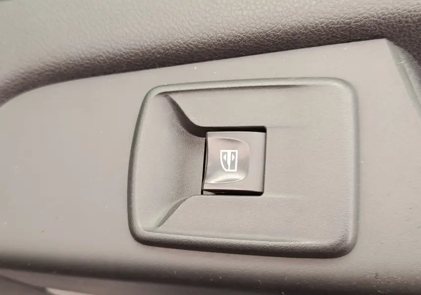 Gros plan sur l'interrupteur de lève-vitre électrique dans l'habitacle du Renault Trafic Fourgon blanc.