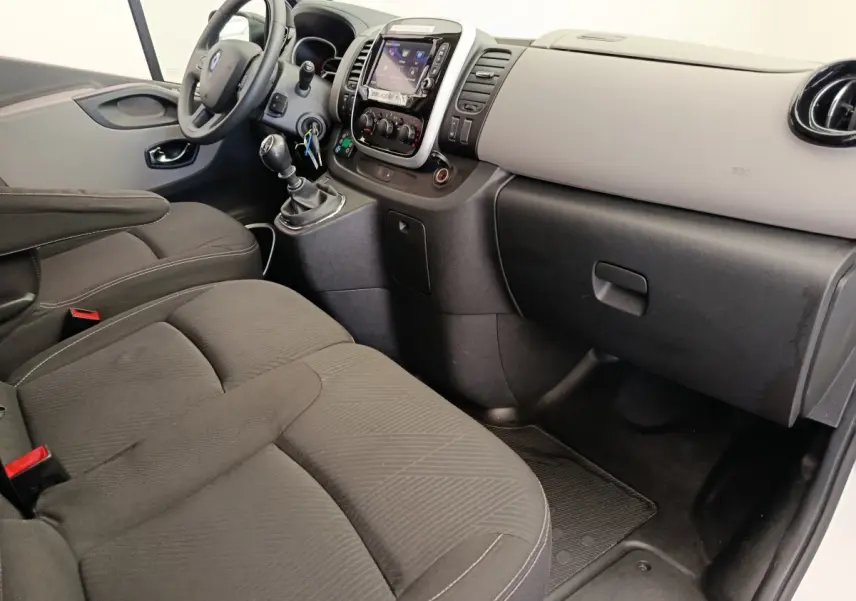 Vue intérieure côté passager du Renault Trafic Fourgon 2017, montrant sièges noirs et tableau de bord clair avec console centrale.