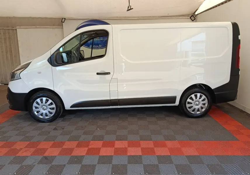 Renault Trafic Fourgon blanc vu de profil côté gauche, avec porte coulissante et jantes acier argentées.