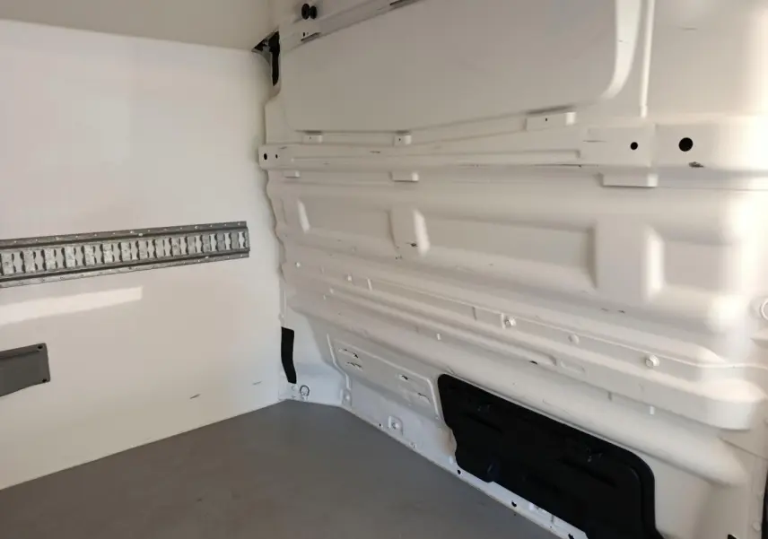 Intérieur du fourgon Renault Trafic blanc, vue latérale droite montrant la cloison pleine et le plancher gris.