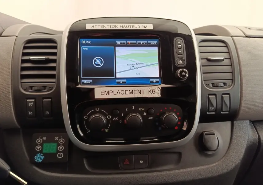 Vue rapprochée du tableau de bord du Renault Trafic blanc, avec écran tactile et commandes de climatisation visibles.