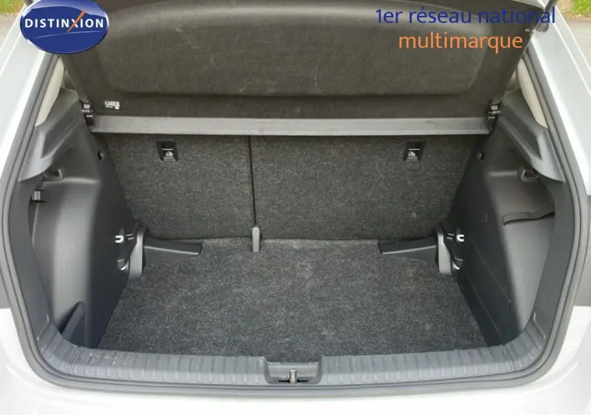 Coffre ouvert vu de l'arrière d'une Skoda Fabia blanc glacier, montrant l'espace de chargement vide et la moquette grise.