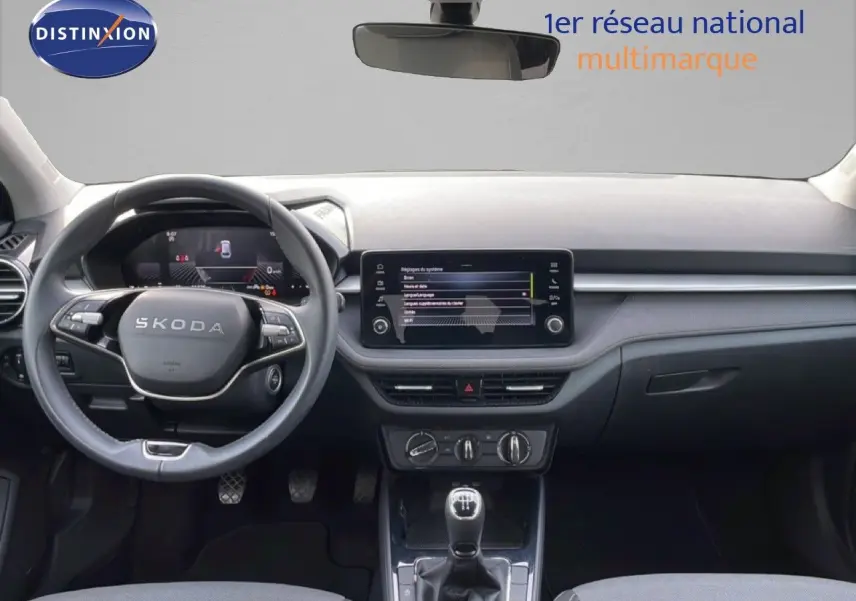 Vue intérieure avant du tableau de bord et volant SKODA Fabia 2025 avec écran tactile et levier de vitesses manuel.