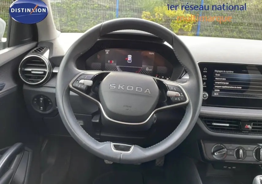 Vue intérieure centrée sur le volant cuir noir SKODA Fabia 2025 avec tableau de bord digital et écran tactile.