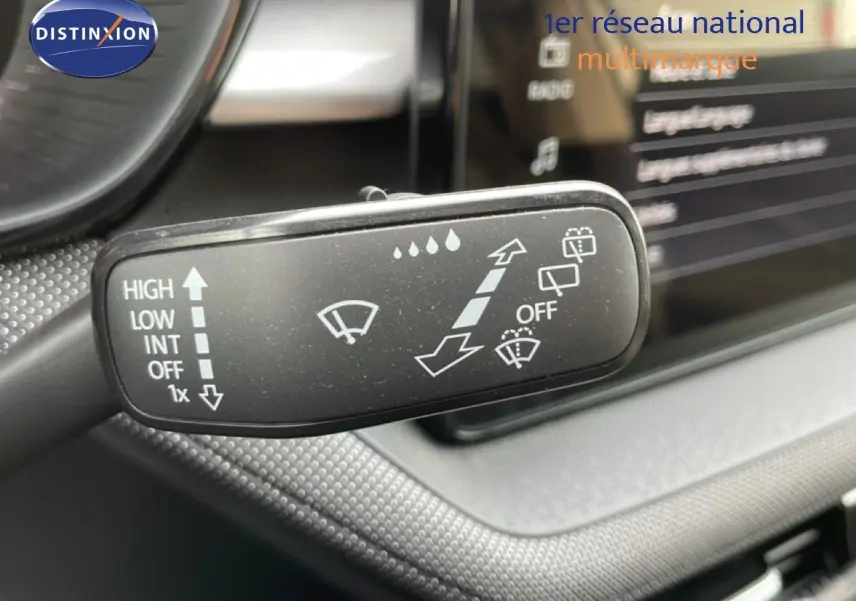 Gros plan sur la commande d’essuie-glace dans l’habitacle d’une Skoda Fabia blanc glacier, tableau de bord en arrière-plan flou.