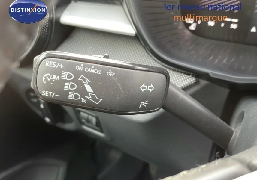 Gros plan sur la commande de régulateur de vitesse à gauche du volant dans l’habitacle d’une Skoda Fabia blanche.