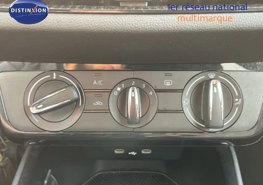 Vue rapprochée des commandes de climatisation d'une Skoda Fabia blanche Glacier, avec boutons rotatifs noirs et chrome.