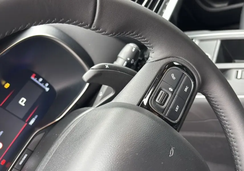 Gros plan sur le volant en cuir noir du Citroën C5 Aircross Hybrid 145, avec commandes intégrées visibles.