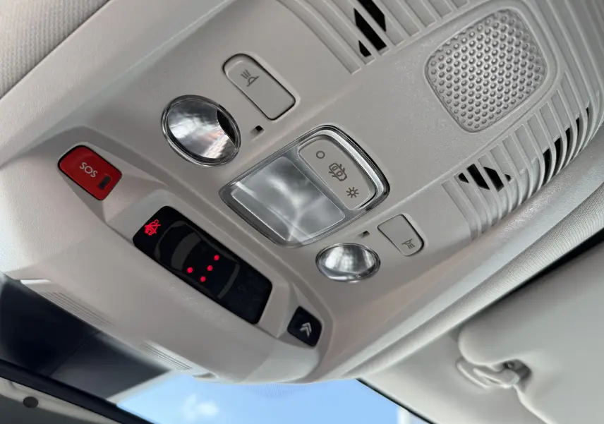 Plafonnier intérieur beige clair du Citroën C5 Aircross Hybrid 2025 avec boutons SOS, éclairages et commandes au plafond.