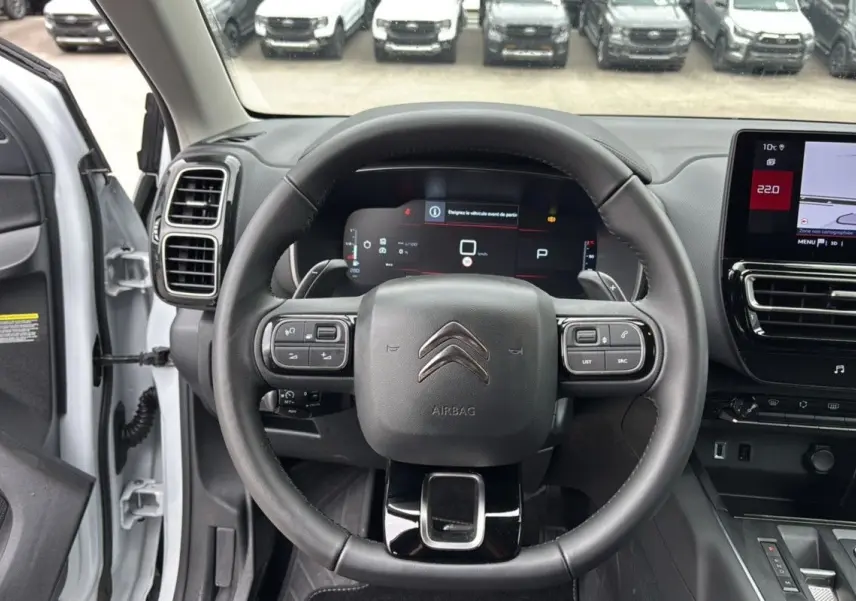Vue intérieure centrée sur le volant du Citroën C5 Aircross blanc Okenite, avec tableau de bord numérique et écran tactile.
