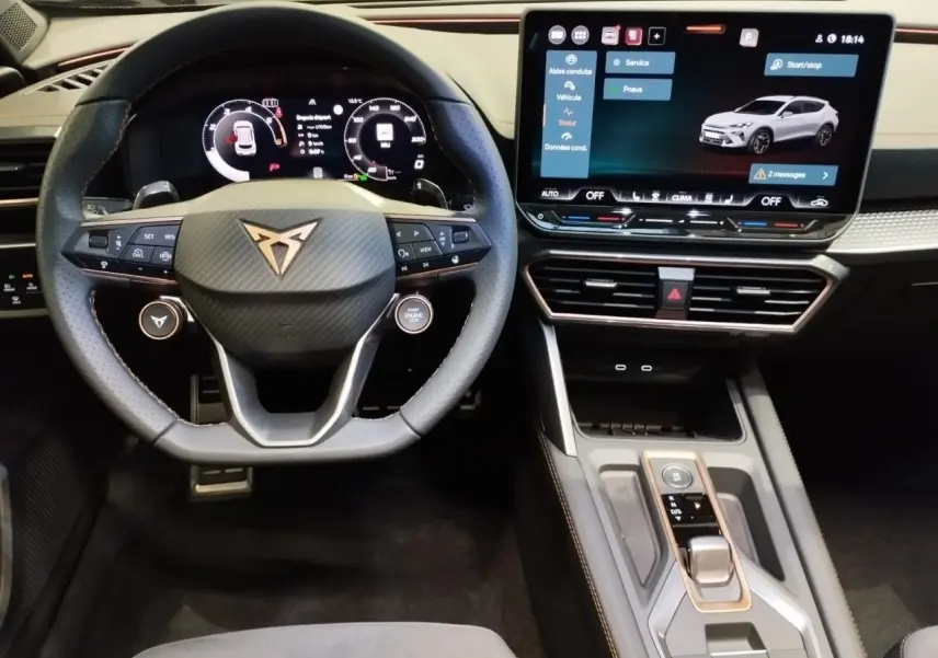 Vue intérieure centrée sur le volant Cupra noir avec logo cuivré et écran tactile HD du tableau de bord.