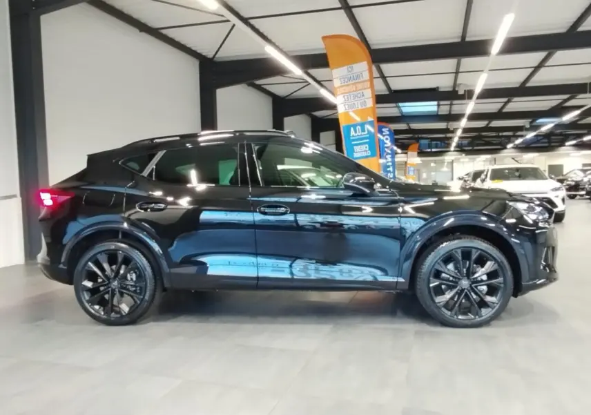 Profil droit du CUPRA Formentor noir métal 2026 avec jantes alliage noires et toit ouvrant panoramique visible en intérieur showroom.