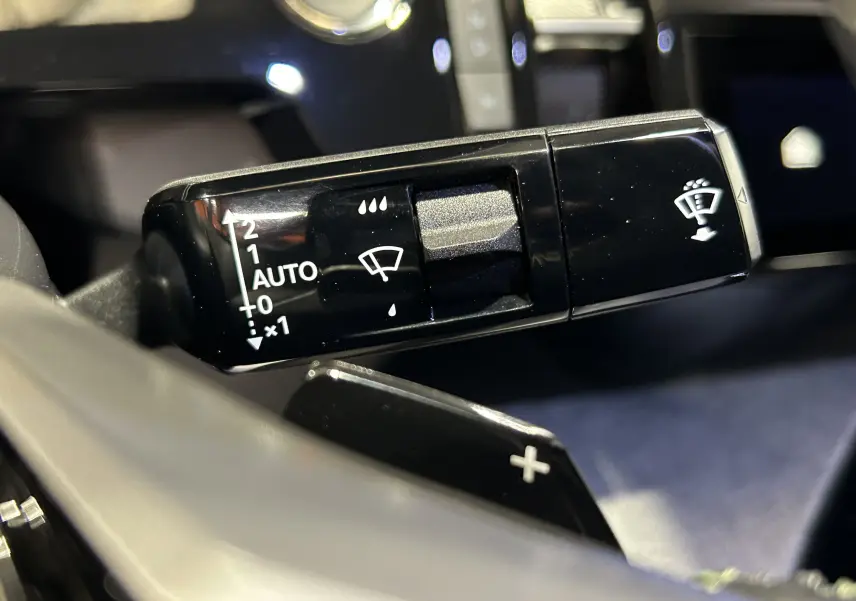Gros plan sur la commande de l’essuie-glace dans l’habitacle noir du Peugeot 3008 III Hybrid blanc Okenite.