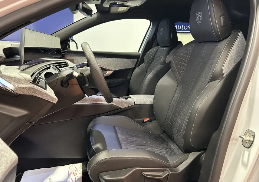 Vue intérieure côté conducteur du Peugeot 3008 Hybrid blanc Okenite, sièges en cuir et tissu avec logo Peugeot brodé.