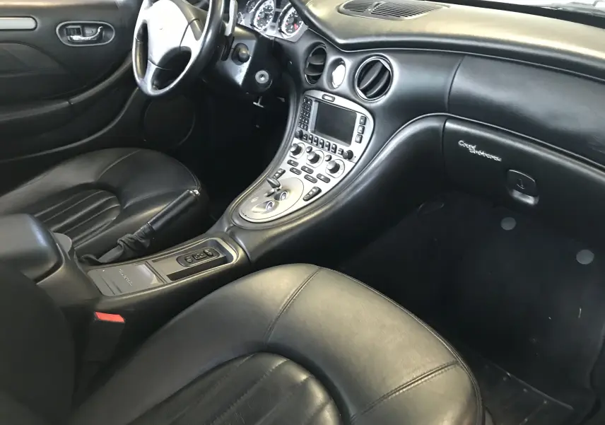 Intérieur cuir noir de Maserati Coupé 2003 vu côté conducteur, avec console centrale et tableau de bord élégants.
