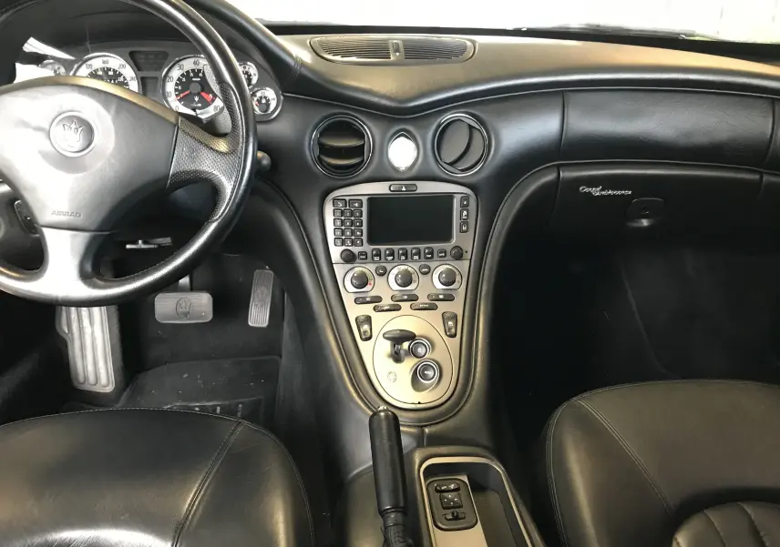 Intérieur noir cuir de la Maserati Coupé 2003, vue centrée sur le tableau de bord et la console centrale.