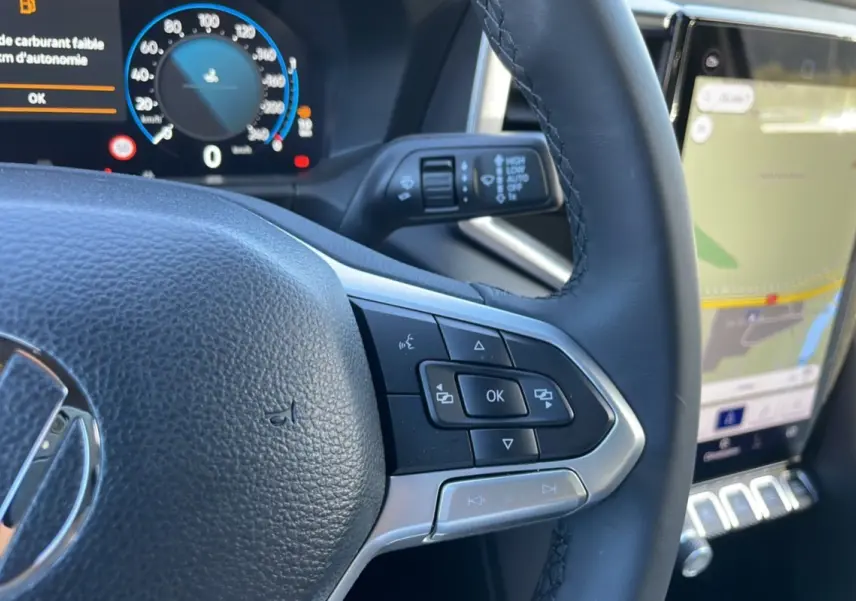 Gros plan sur le volant en cuir du Volkswagen Amarok blanc 2025, avec commandes multifonctions et tableau de bord numérique.