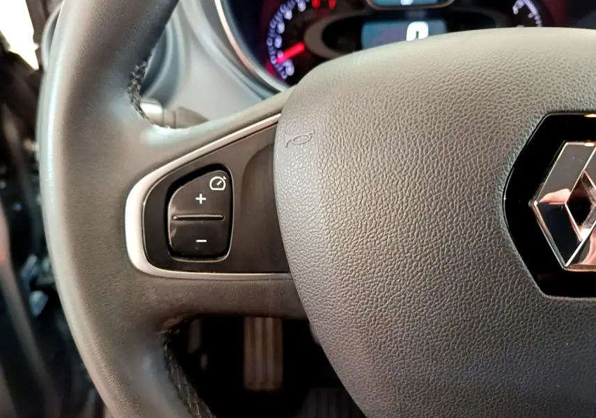 Gros plan sur le volant cuir gris du Renault Captur Business, avec commandes de régulateur de vitesse visibles à gauche.