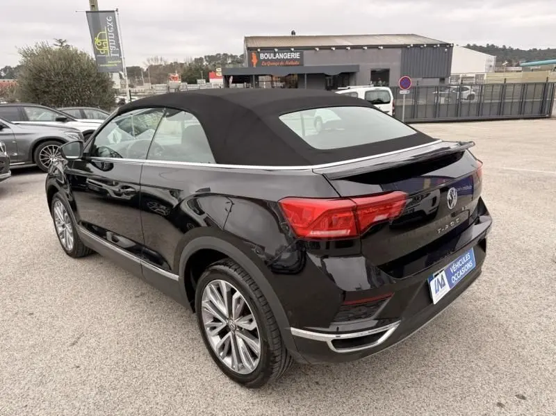 Volkswagen T-Roc Cabriolet noir métal vu en 3/4 arrière droit, capote noire fermée et jantes alliage visibles.