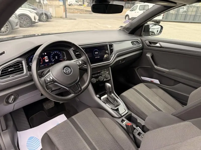Vue intérieure côté conducteur du Volkswagen T-Roc Cabriolet noir métal 2020, avec tableau de bord digital et console centrale moderne.