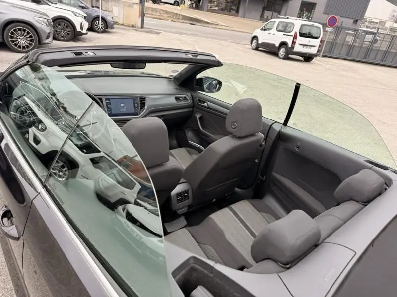 Vue intérieure en plongée du côté gauche du Volkswagen T-Roc Cabriolet noir métal 2020, toit ouvert, sièges en tissu gris.