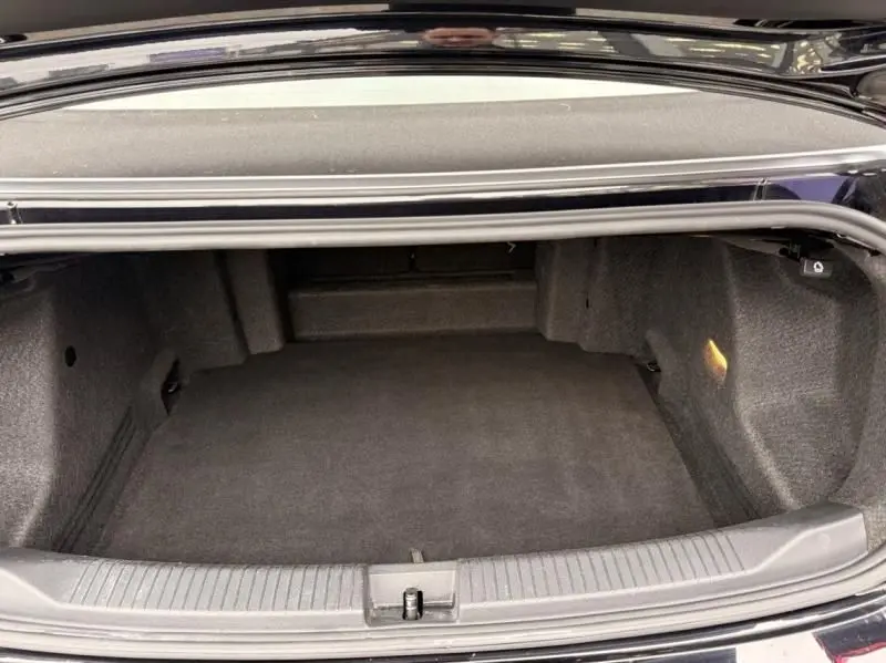 Coffre ouvert du Volkswagen T-Roc Cabriolet noir métal, vue de l’arrière montrant l’espace de chargement vide.