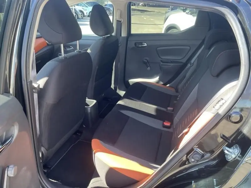 Vue intérieure arrière côté droit de la Nissan Micra noire 2017, montrant les sièges arrière avec détails orange et tissu noir.