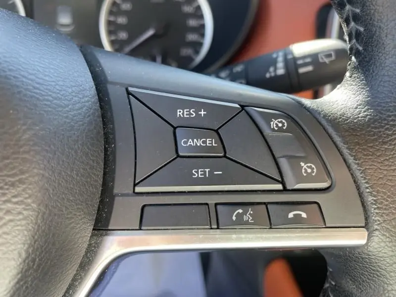 Gros plan sur les commandes de régulateur de vitesse et téléphone au volant noir de la Nissan Micra 2017.
