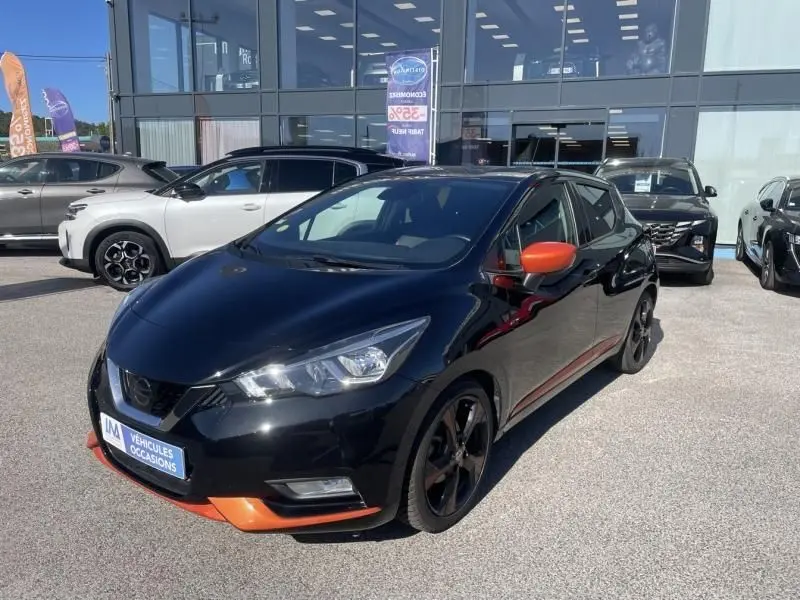 Nissan Micra 1.5 DCI 90 N-Connecta noire vue 3/4 avant droit avec rétroviseurs et détails orange contrastants.