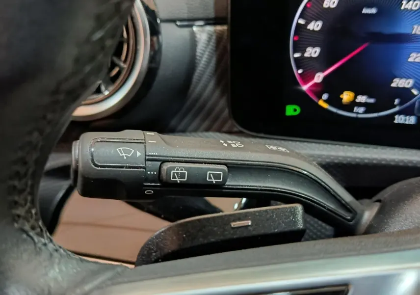 Gros plan sur la manette d’essuie-glace à gauche du volant dans l’habitacle gris foncé du Mercedes GLA 250 e 2023.