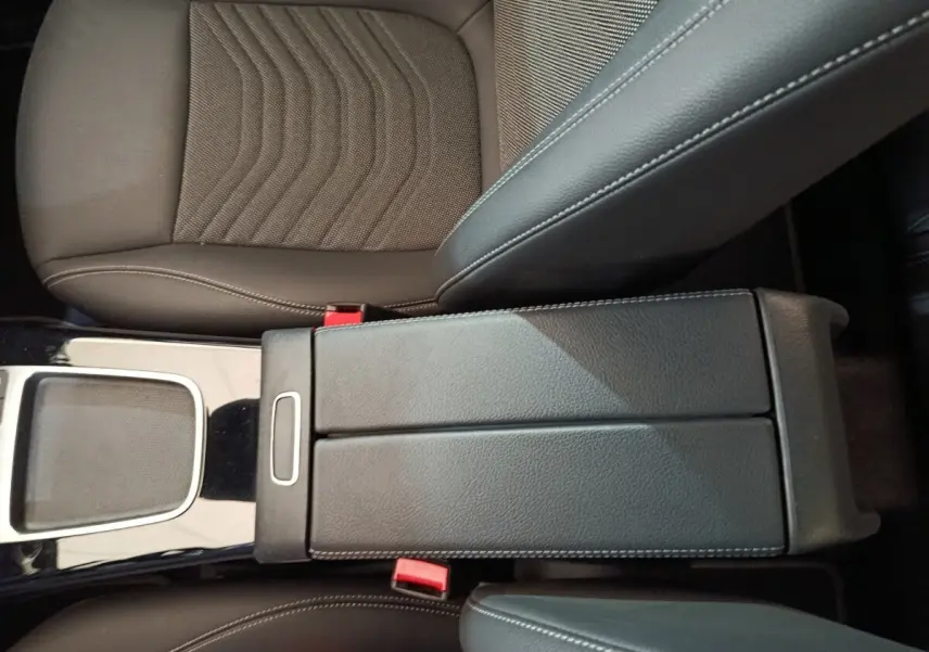Vue rapprochée de l'accoudoir central en cuir noir et des sièges avant marron du Mercedes GLA 250 e Business Line 2023.