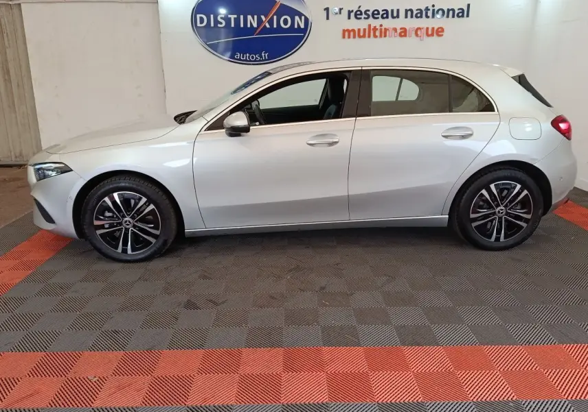 Vue latérale droite d'une Mercedes GLA 250 e Business Line hybride rechargeable gris clair en intérieur showroom.