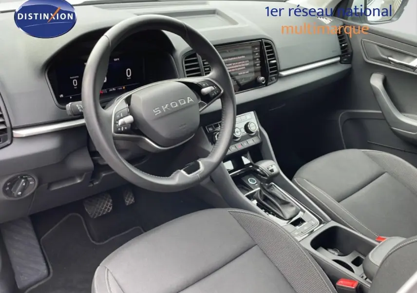 Vue intérieure côté conducteur du Skoda Karoq blanc glacier 2025, avec tableau de bord numérique et volant multifonction cuir.