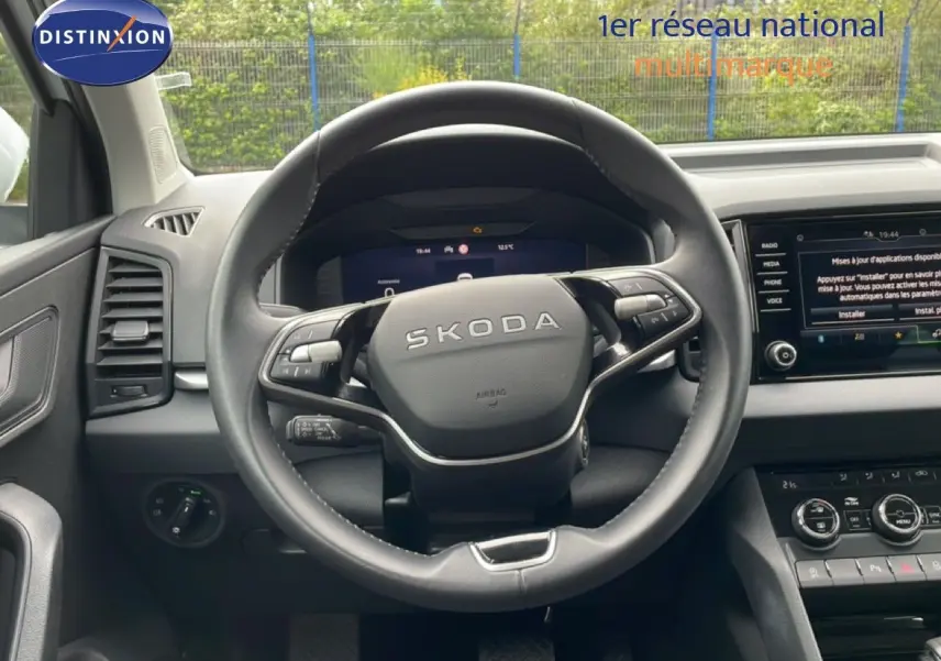 Vue intérieure centrée sur le volant noir du Skoda Karoq 2025 avec tableau de bord et écran tactile visibles.