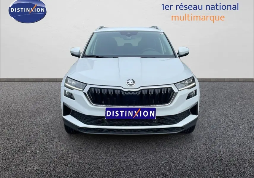 Vue frontale d'un Skoda Karoq blanc glacier 2025 avec calandre noire et phares LED distinctifs.