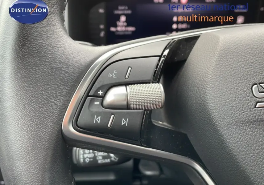 Vue rapprochée du volant multifonction noir du Skoda Karoq blanc glacier, mettant en valeur les commandes audio et vocales.