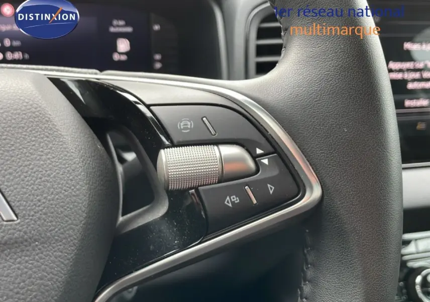 Gros plan sur les commandes au volant en cuir noir du Skoda Karoq blanc glacier, avec tableau de bord numérique en arrière-plan.