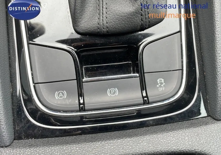 Gros plan sur les commandes de la console centrale noire du Skoda Karoq blanc glacier, avec levier de vitesse en cuir.