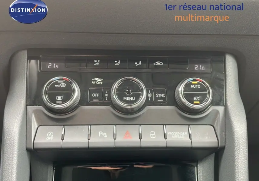 Gros plan sur la console centrale de la Skoda Karoq blanc glacier, montrant les commandes de climatisation et boutons fonctionnels.