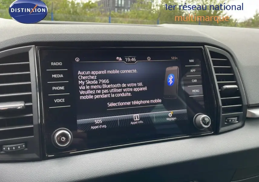 Écran central tactile du tableau de bord du Skoda Karoq blanc glacier, affichant le menu Bluetooth et les options multimédia.
