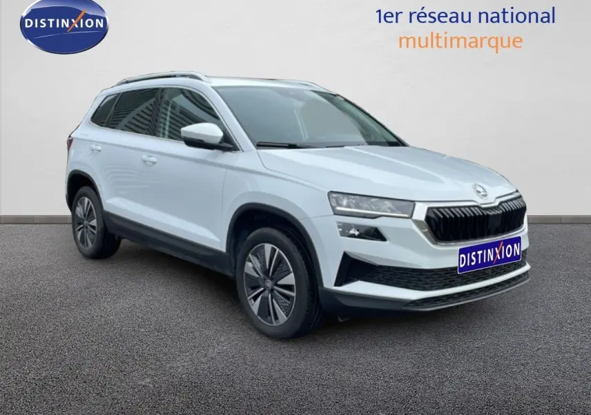 Vue 3/4 avant droit d'un Skoda Karoq blanc glacier avec calandre noire et jantes bi-ton.