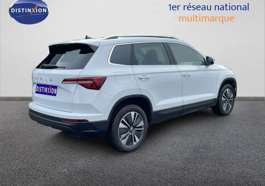 Vue 3/4 arrière droite du SUV SKODA KAROQ blanc glacier 2025 avec jantes bi-ton et feux arrière LED distinctifs.