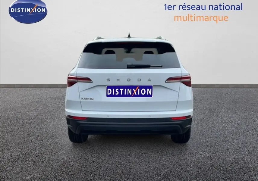 Vue arrière d'un Skoda Karoq blanc glacier 2025 avec feux arrière LED et logo SKODA visible.